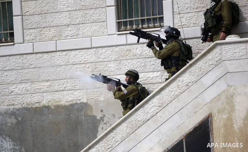 A member of Israeli security forces fires tear gas towards Palestinian youths during clashes following the funeral of 27-year-old Palestinian Mohammed Jasser Karakra, in the Sinjil village, in the occupied West Bank city...