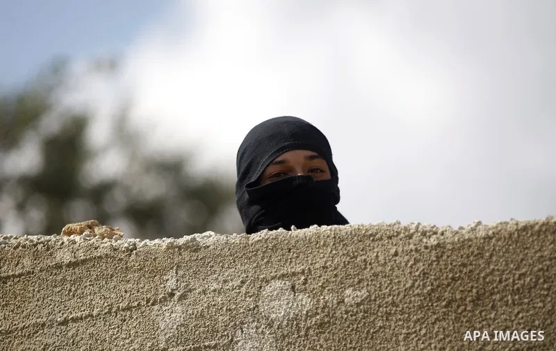 A masked Palestinian youth looks on during clashes with Israeli security forces following the funeral of 27-year-old Palestinian Mohammed Jasser Karakra, in the Sinjil village, in the occupied West Bank city of Ramallah,...