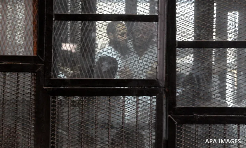 Members of Ansar Bayt al-Maqdis stand behind bars at a courtroom, during their trial in Cairo on April 18, 2015. 213 defendant members of Ansar al-Bayt al-Maqdis, including 140 defendants locked up, for committing a crim...