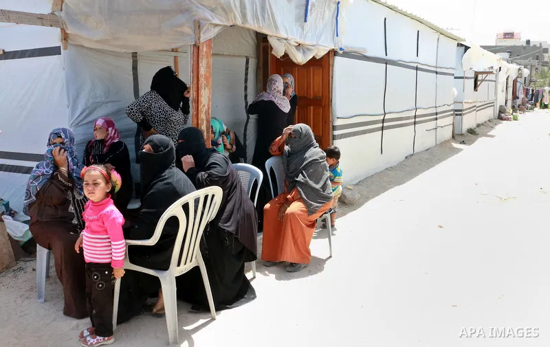Palestinian women, who lost their houses during the 50-day Israeli war in the summer of 2014, sit outside their containers during the visit of James Rawley, United Nations' humanitarian coordinator for the Palestinian te...