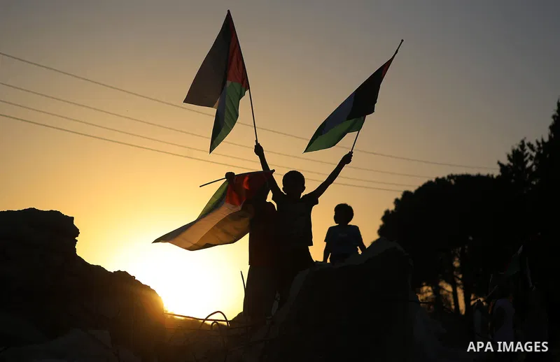 Palestinian children wave their national flags over debris of a house that was demolished by Israeli army early today, in the West Bank village of Nabi Saleh, near Ramallah, April 28, 2015. Israeli forces raided the vill...