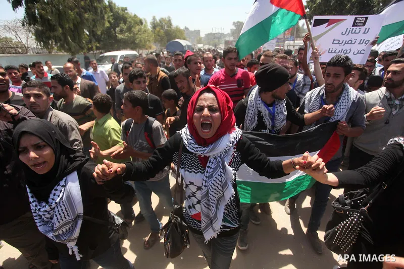 Palestinian youths chant slogans during a protest calling for an end in the political division and opening the Rafah crossing border, in Gaza city, on April 29, 2015. Photo by Ashraf Amra
