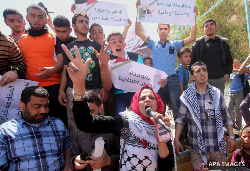 Palestinian youths chant slogans during a protest calling for an end in the political division and opening the Rafah crossing border, in Gaza city, on April 29, 2015. Photo by Ashraf Amra