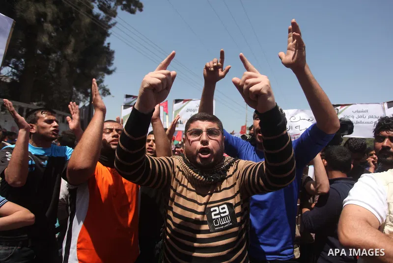 Palestinian youths chant slogans during a protest calling for an end in the political division and opening the Rafah crossing border, in Gaza city, on April 29, 2015. Photo by Ashraf Amra