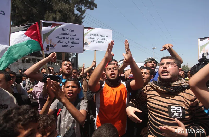 Palestinian youths chant slogans during a protest calling for an end in the political division and opening the Rafah crossing border, in Gaza city, on April 29, 2015. Photo by Ashraf Amra