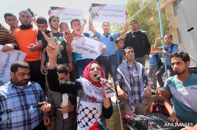 Palestinian youths chant slogans during a protest calling for an end in the political division and opening the Rafah crossing border, in Gaza city, on April 29, 2015. Photo by Ashraf Amra