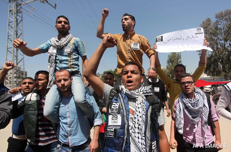Palestinian youths chant slogans during a protest calling for an end in the political division and opening the Rafah crossing border, in Gaza city, on April 29, 2015. Photo by Ashraf Amra