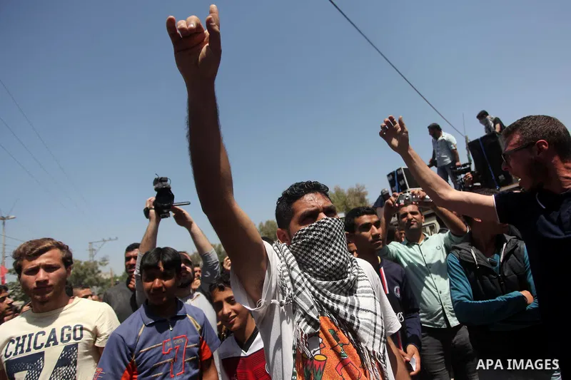 Palestinian youths chant slogans during a protest calling for an end in the political division and opening the Rafah crossing border, in Gaza city, on April 29, 2015. Photo by Ashraf Amra