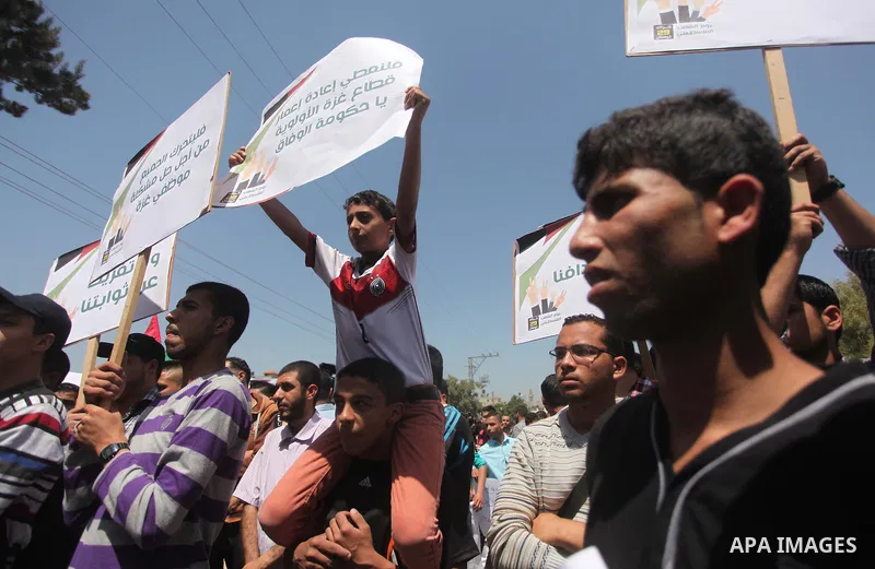 Palestinian youths chant slogans during a protest calling for an end in the political division and opening the Rafah crossing border, in Gaza city, on April 29, 2015. Photo by Ashraf Amra