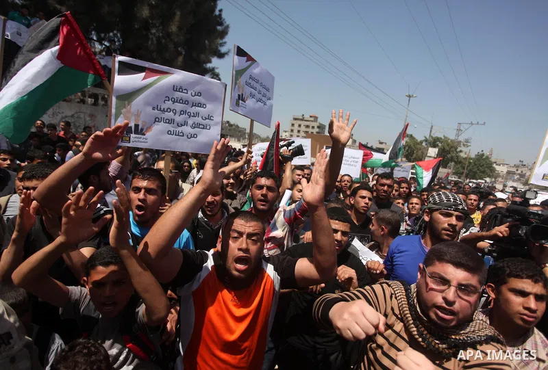 Palestinian youths chant slogans during a protest calling for an end in the political division and opening the Rafah crossing border, in Gaza city, on April 29, 2015. Photo by Ashraf Amra