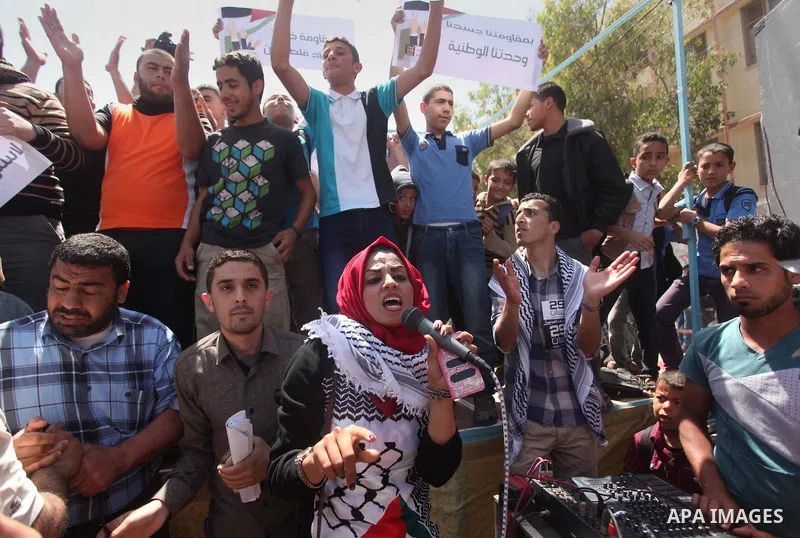 Palestinian youths chant slogans during a protest calling for an end in the political division and opening the Rafah crossing border, in Gaza city, on April 29, 2015. Photo by Ashraf Amra