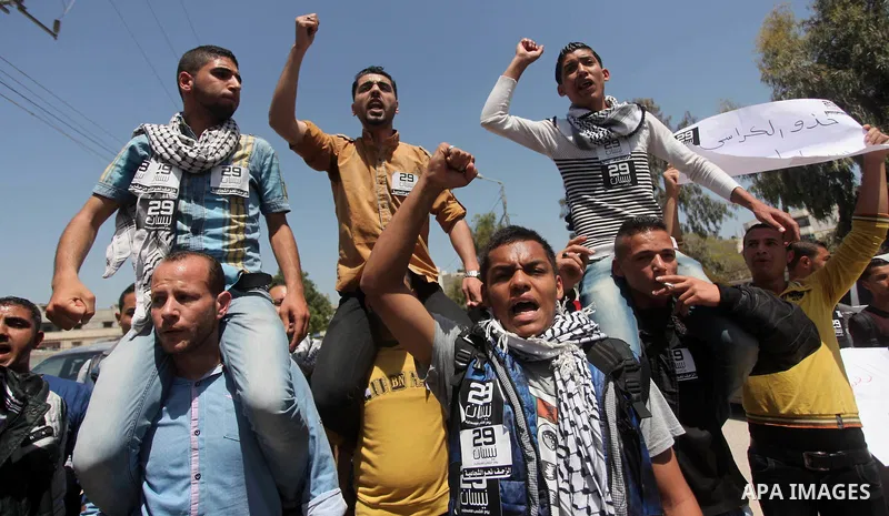 Palestinian youths chant slogans during a protest calling for an end in the political division and opening the Rafah crossing border, in Gaza city, on April 29, 2015. Photo by Ashraf Amra