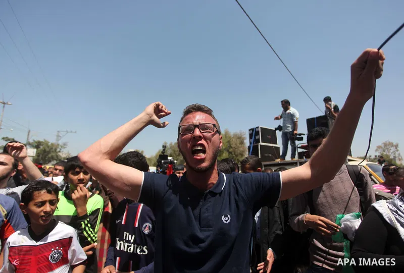 Palestinian youths chant slogans during a protest calling for an end in the political division and opening the Rafah crossing border, in Gaza city, on April 29, 2015. Photo by Ashraf Amra