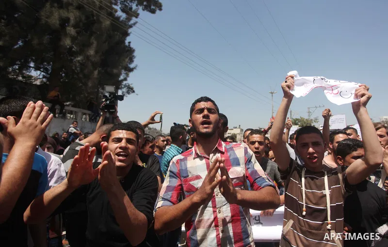 Palestinian youths chant slogans during a protest calling for an end in the political division and opening the Rafah crossing border, in Gaza city, on April 29, 2015. Photo by Ashraf Amra