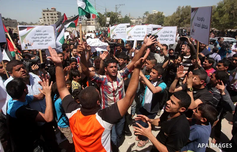Palestinian youths chant slogans during a protest calling for an end in the political division and opening the Rafah crossing border, in Gaza city, on April 29, 2015. Photo by Ashraf Amra