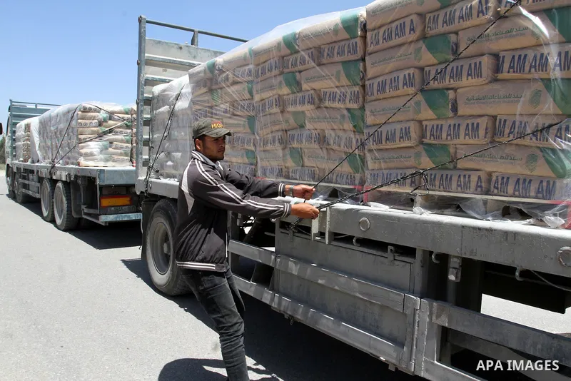 A Palestinian worker adjusts bags of cement loaded onto a truck after it entered the southern Gaza Strip from Israel through the Kerem Shalom crossing in Rafah on April 29, 2015. Photo by Abed Rahim Khatib