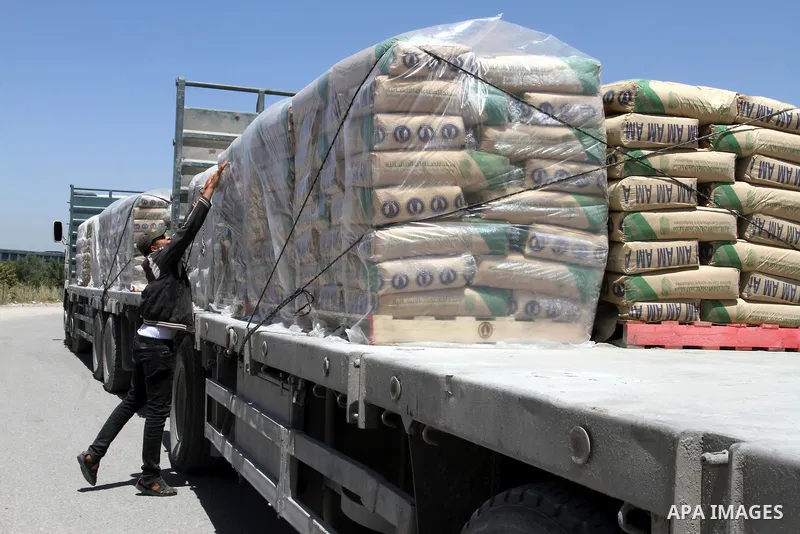 A Palestinian worker adjusts bags of cement loaded onto a truck after it entered the southern Gaza Strip from Israel through the Kerem Shalom crossing in Rafah on April 29, 2015. Photo by Abed Rahim Khatib