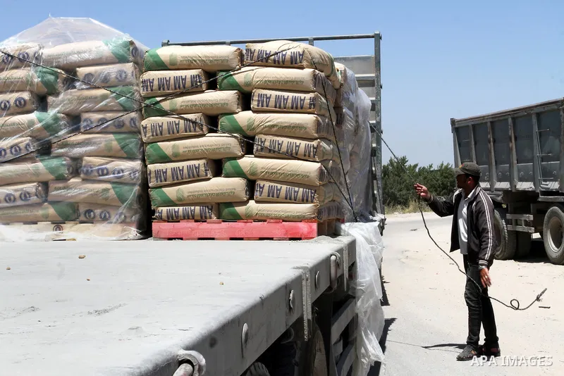 A Palestinian worker adjusts bags of cement loaded onto a truck after it entered the southern Gaza Strip from Israel through the Kerem Shalom crossing in Rafah on April 29, 2015. Photo by Abed Rahim Khatib