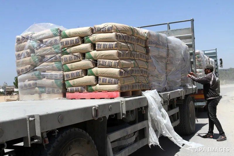 A Palestinian worker adjusts bags of cement loaded onto a truck after it entered the southern Gaza Strip from Israel through the Kerem Shalom crossing in Rafah on April 29, 2015. Photo by Abed Rahim Khatib