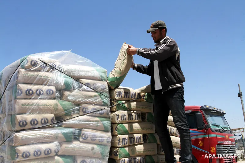 A Palestinian worker adjusts bags of cement loaded onto a truck after it entered the southern Gaza Strip from Israel through the Kerem Shalom crossing in Rafah on April 29, 2015. Photo by Abed Rahim Khatib