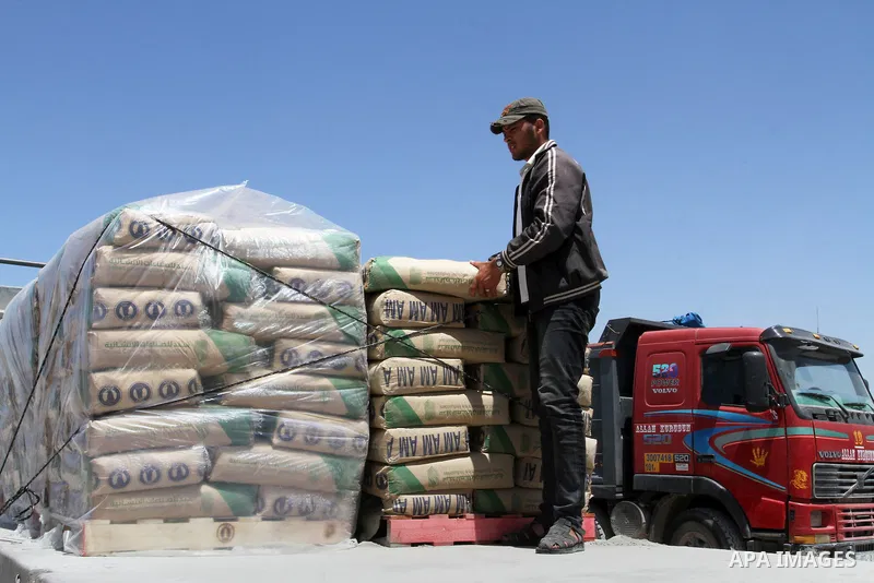 A Palestinian worker adjusts bags of cement loaded onto a truck after it entered the southern Gaza Strip from Israel through the Kerem Shalom crossing in Rafah on April 29, 2015. Photo by Abed Rahim Khatib