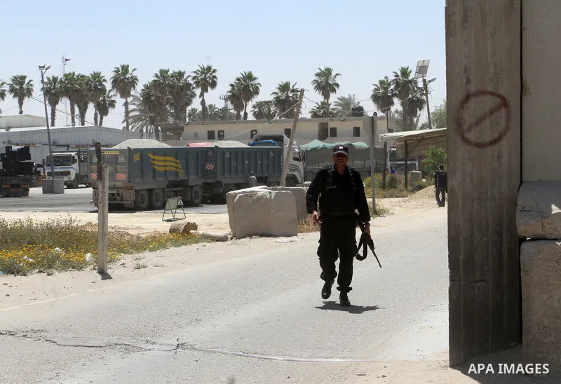 A Palestinian police officer walks past trucks carrying supplies after they entered the southern Gaza Strip from Israel through the Kerem Shalom crossing in Rafah on April 29, 2015. Photo by Abed Rahim Khatib