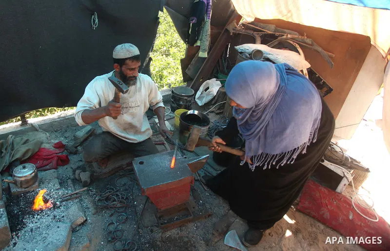 Palestinian blacksmith Ibraheem Mustafa, 40-year-old, with his wife, hammer heated steel to shape a knife, at their small workshop in Gaza city on April 30, 2015. The ILO estimates that the 2014 conflict in Gaza raised u...