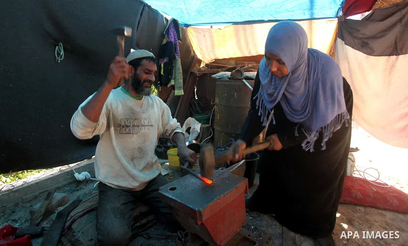 Palestinian blacksmith Ibraheem Mustafa, 40-year-old, with his wife, hammer heated steel to shape a knife, at their small workshop in Gaza city on April 30, 2015. The ILO estimates that the 2014 conflict in Gaza raised u...