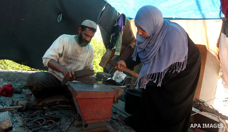 Palestinian blacksmith Ibraheem Mustafa, 40-year-old, with his wife, hammer heated steel to shape a knife, at their small workshop in Gaza city on April 30, 2015. The ILO estimates that the 2014 conflict in Gaza raised u...