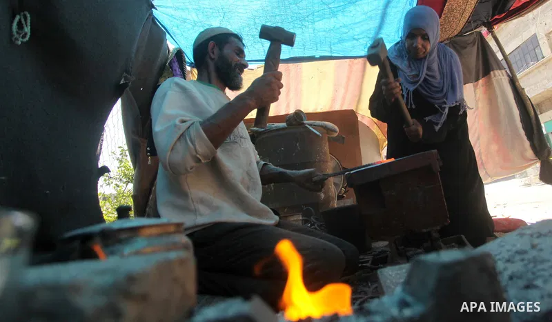 Palestinian blacksmith Ibraheem Mustafa, 40-year-old, with his wife, hammer heated steel to shape a knife, at their small workshop in Gaza city on April 30, 2015. The ILO estimates that the 2014 conflict in Gaza raised u...
