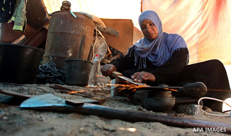 Aysha Ali, the wife of Ibraheem Mustafa, a 40-year-old Palestinian blacksmith, sharpens a handmade knife, at their small workshop in Gaza city on April 30, 2015. The ILO estimates that the 2014 conflict in Gaza raised un...