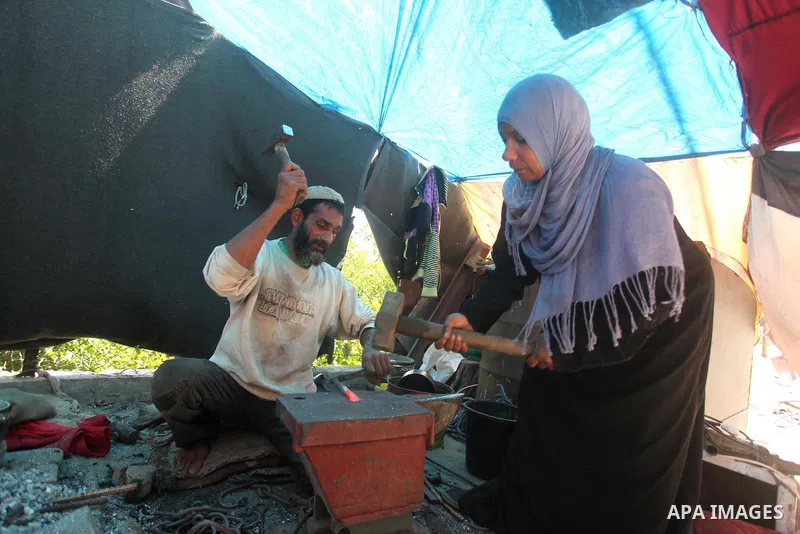 Palestinian blacksmith Ibraheem Mustafa, 40-year-old, with his wife, hammer heated steel to shape a knife, at their small workshop in Gaza city on April 30, 2015. The ILO estimates that the 2014 conflict in Gaza raised u...