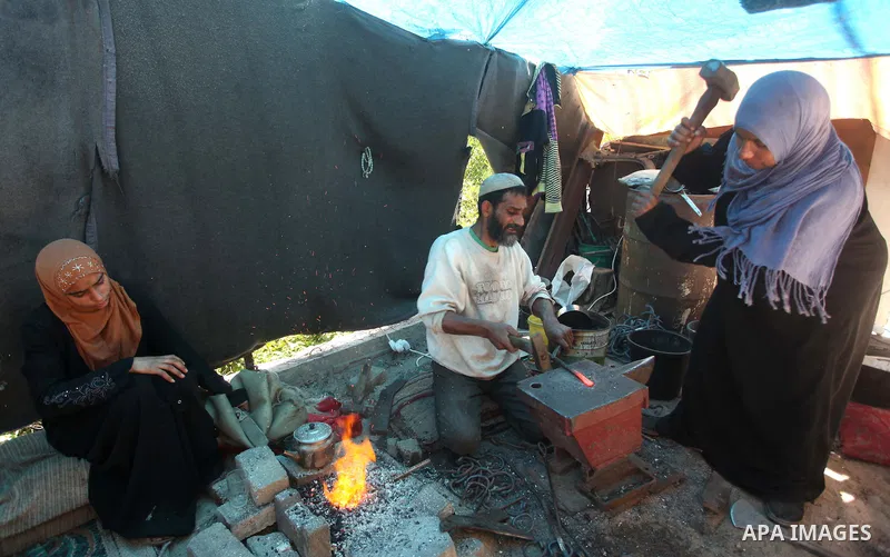Palestinian blacksmith Ibraheem Mustafa, 40-year-old, with his wife, hammer heated steel to shape a knife, at their small workshop in Gaza city on April 30, 2015. The ILO estimates that the 2014 conflict in Gaza raised u...