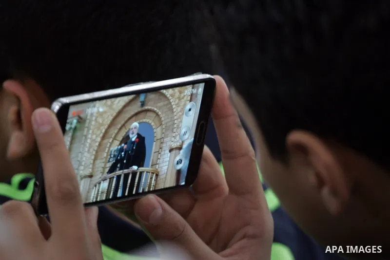 A Palestinian youth takes pictures by his mobile as senior Hamas leader Ismail Haniyeh, gives a speech during Friday prayers in the southern Gaza Strip town of Rafah on May 1, 2015. Photo by Abed Rahim Khatib