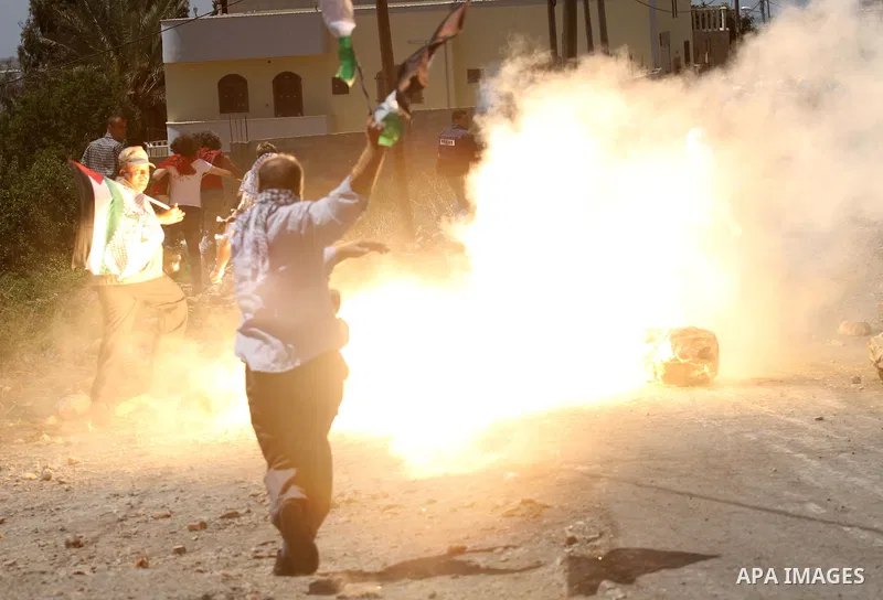 Palestinian protester react as a sound bomb fired by Israeli security forces explodes, during clashes following a protest against the expropriation of Palestinian land by Israel in the West Bank village of Kafr Qaddum, n...
