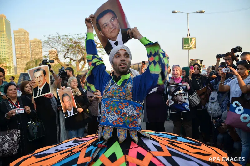 A dancer performs as supporters of former President Hosni Mubarak holds his picture during a celebration to mark his 87th birthday, outside Maadi military hospital, near Cairo on May 4, 2015. An Egyptian legal authority...