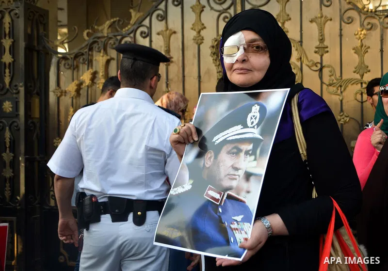 An Egyptian supporter of former President Hosni Mubarak holds his picture during a celebration to mark his 87th birthday, outside Maadi military hospital, near Cairo on May 4, 2015. An Egyptian legal authority on Monday...