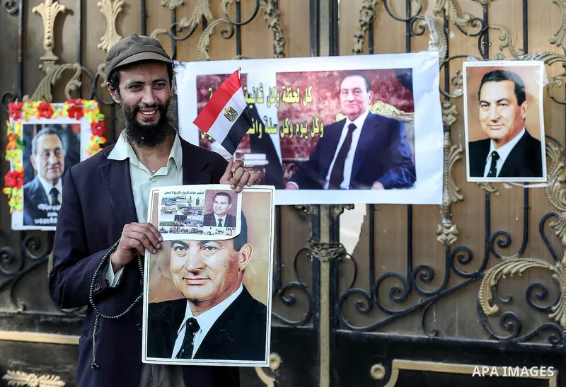 An Egyptian supporter of former President Hosni Mubarak holds his picture during a celebration to mark his 87th birthday, outside Maadi military hospital, near Cairo on May 4, 2015. An Egyptian legal authority on Monday...