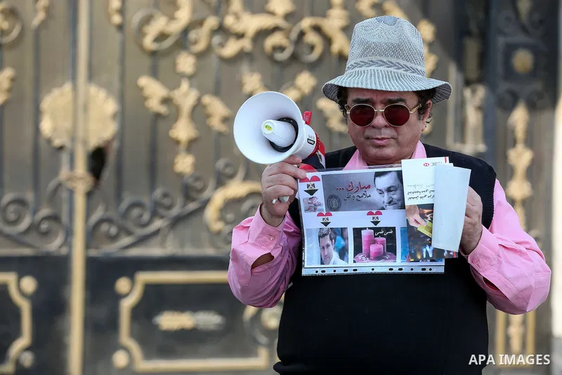 An Egyptian supporter of former President Hosni Mubarak holds his picture during a celebration to mark his 87th birthday, outside Maadi military hospital, near Cairo on May 4, 2015. An Egyptian legal authority on Monday...