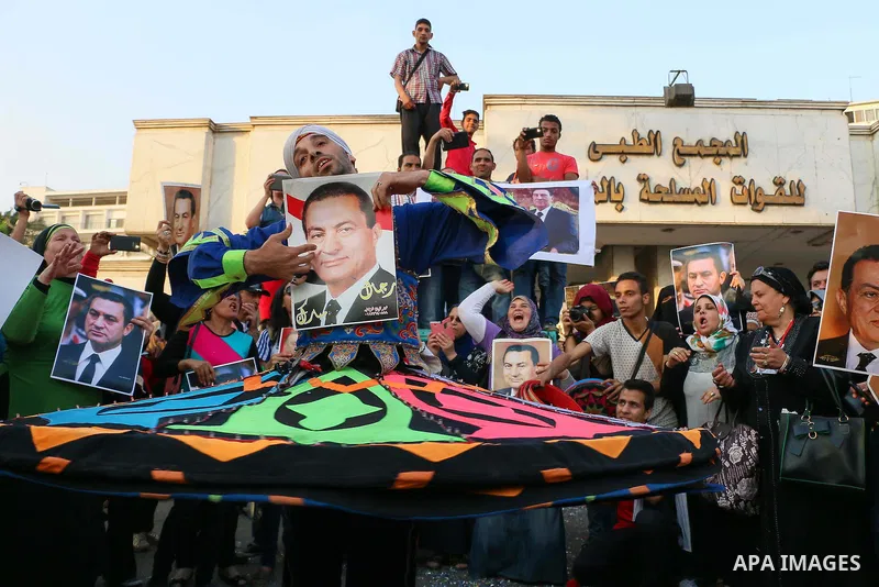 Egyptian supporters of former President Hosni Mubarak hold his picture during a celebration to mark his 87th birthday, outside Maadi military hospital, near Cairo on May 4, 2015. An Egyptian legal authority on Monday rul...