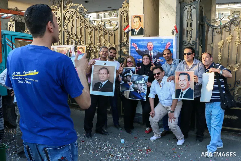 Egyptian supporters of former President Hosni Mubarak take pose for a photograph with his pictures as they celebrate to mark his 87th birthday, outside Maadi military hospital, near Cairo on May 4, 2015. An Egyptian lega...