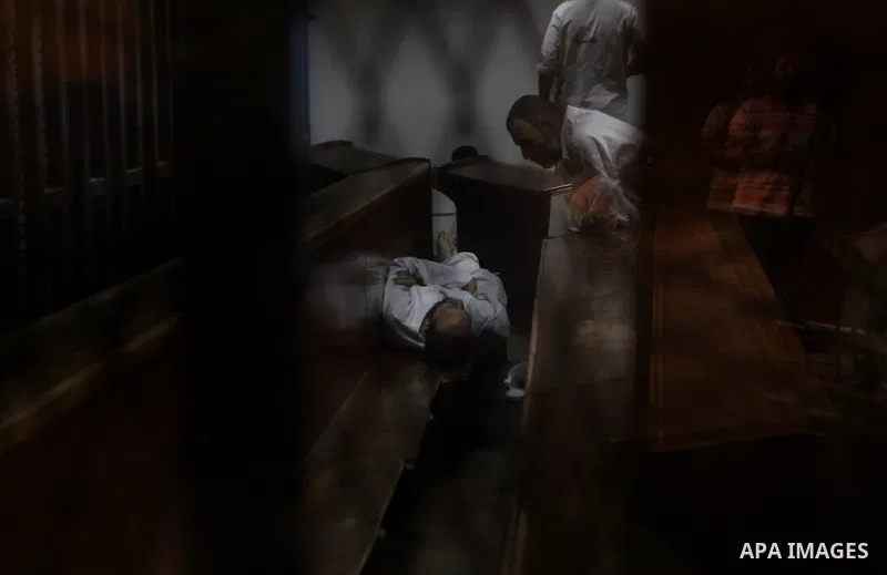 Egyptian defendants are seen behind bars during their trial in a case of the "communicating with Qatar" at the court, in Cairo, on May 5, 2015. Photo by Amr Sayed