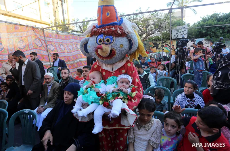 A clown carries twins of a Palestinian prisoner in Israeli jails, who were born from his smuggled sperm, during a protest demanding visit of their father, outside the Red Cross office, in Gaza city on May 7, 2015. Some 2...