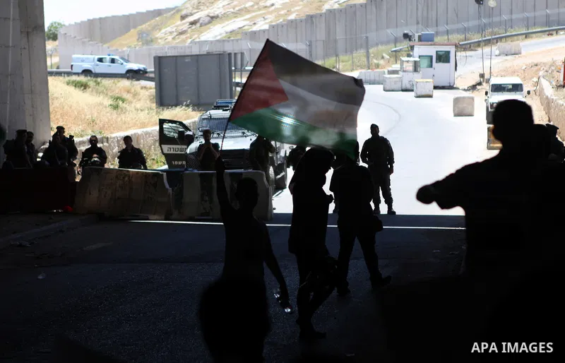 Palestinian protesters from the East Jerusalem village of al-Zaim, wave Palestinian flags as they confront Israeli Border Police during a protest demanding the opening of the only gate in the separated barrier leading fr...