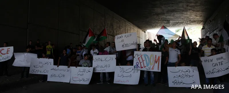 Palestinian protesters from the East Jerusalem village of al-Zaim, wave Palestinian flags as they confront Israeli Border Police during a protest demanding the opening of the only gate in the separated barrier leading fr...
