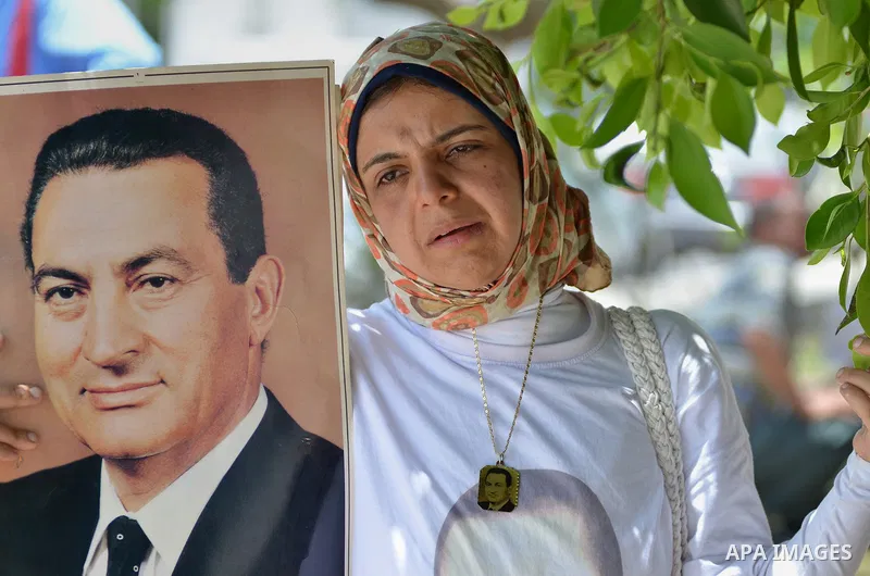 A Supporter of Egypt's former president Hosni Mubarak, holds his pictures after his verdict hearing in a retrial for embezzlement outside the Maadi military hospital, on May 9, 2015 in the capital Cairo. The Egyptian cou...