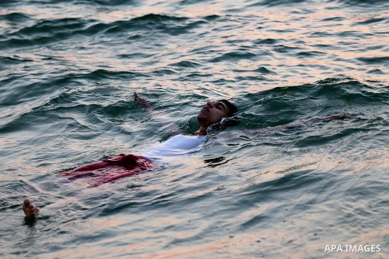 A Palestinian man swims in Gaza sea during sunset on May 9, 2015. Photo by Mohammed Asad