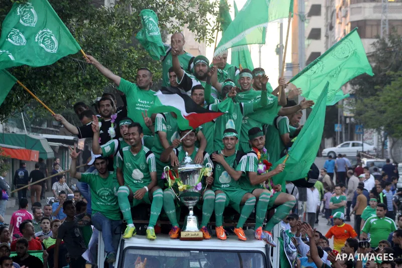 Palestinian members of al-Shijaiyah football club with their fans, celebrate winning Gaza league championship, near the rubbles of houses which where destroyed during the recent Israeli war in the summer of 2014, at al-S...