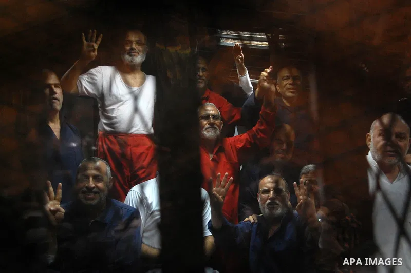 Muslim Brotherhood's Supreme Guide Mohamed Badie sits behind bars with other Muslim Brotherhood members at a court in the outskirts of Cairo, Egypt May 16, 2015. An Egyptian court on Saturday sought the death penalty for...