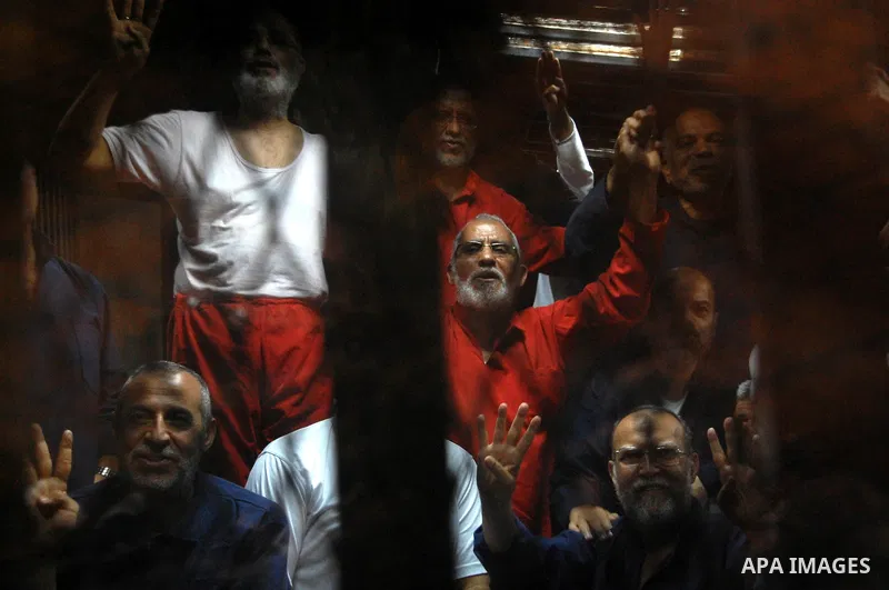 Muslim Brotherhood's Supreme Guide Mohamed Badie sits behind bars with other Muslim Brotherhood members at a court in the outskirts of Cairo, Egypt May 16, 2015. An Egyptian court on Saturday sought the death penalty for...